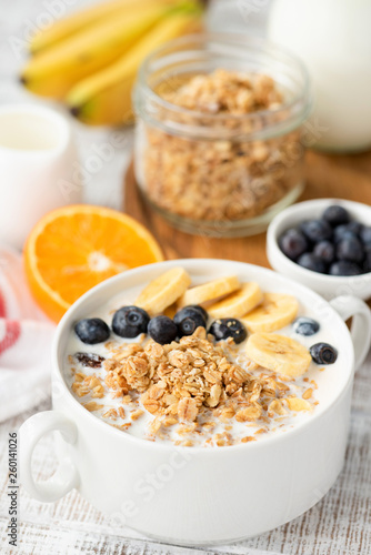 Bowl of granola with milk and berries. Healthy breakfast cereal food on white table