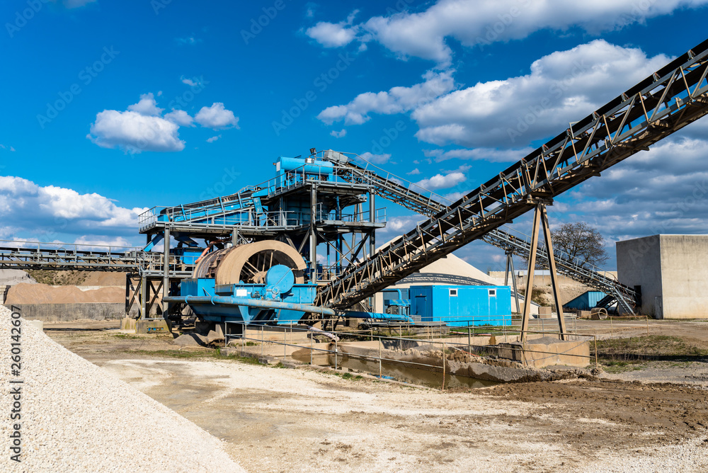 Machine for transferring gravel, spoil for transport belts on blue sky at an industrial cement plant. Machine for transferring gravel, spoil for transport belts on blue sky at an industrial cement plant.