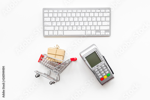 Online shopping concept with trolley near card machine, keyboard on white background top view