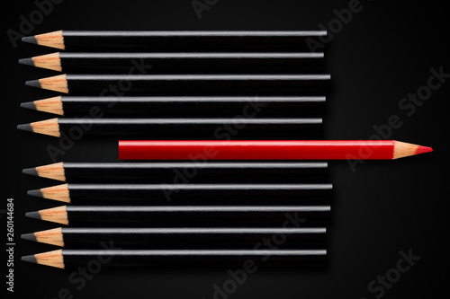 Business concept of disruption, leadership or think different; red pencil in row of black pencils pointing in opposite direction photo