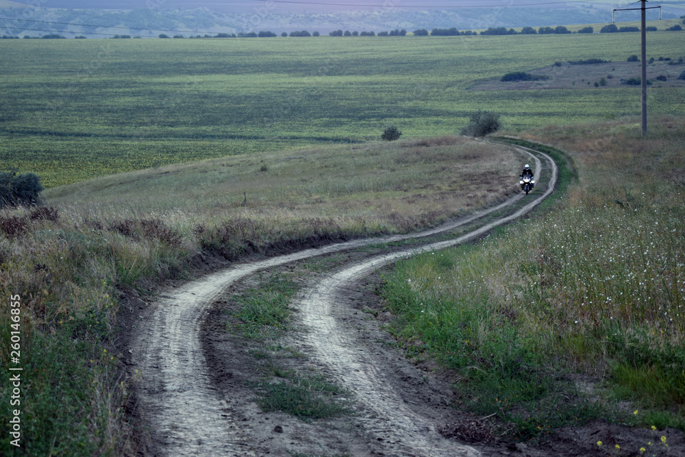 Motorcycle traveler riding on dirty road between fields. Republic of Moldova landscape. Motorcycle traveler riding on dirty road between fields. Republic of Moldova landscape.