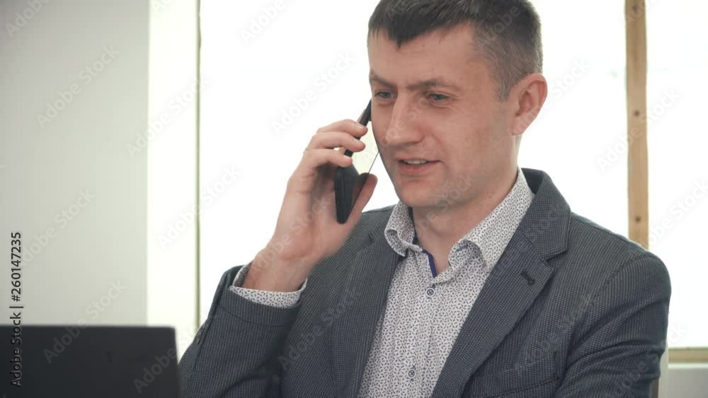 Adult businessman talking on phone in office Adult businessman talking on phone in office