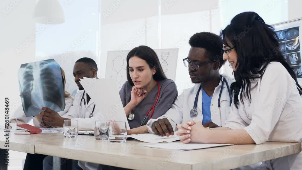 Team of multiethnic young doctors having a meeting in conference room in the modern hospital. Group of multiethnic doctors are medical studying studying disease histories patients Team of multiethnic young doctors having a meeting in conference room in the modern hospital. Group of multiethnic doctors are medical studying studying disease histories patients