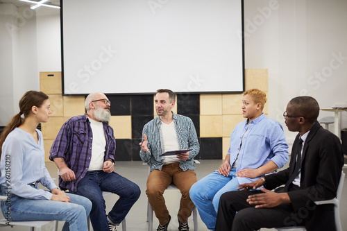 Obraz na płótnie Portrait of mature psychologist leading therapy session in support group, copy s