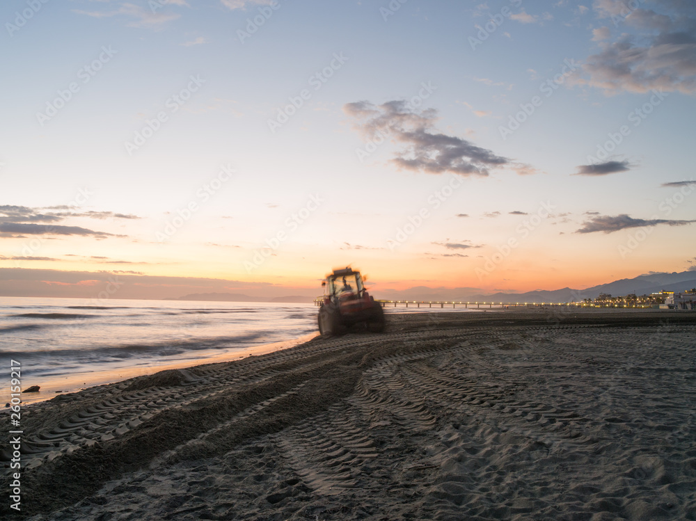 Tractor tyre tracks in beach sand at sunset, tractors are used in italy beach of viareggio to clean and prepare the sand for summer season. Tractor tyre tracks in beach sand at sunset, tractors are used in italy beach of viareggio to clean and prepare the sand for summer season.