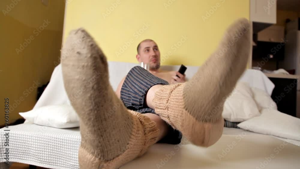 Bald nasty fat man is lying on the sofa, watching TV and eating chips and Coca-Cola Bald nasty fat man is lying on the sofa, watching TV and eating chips and Coca-Cola