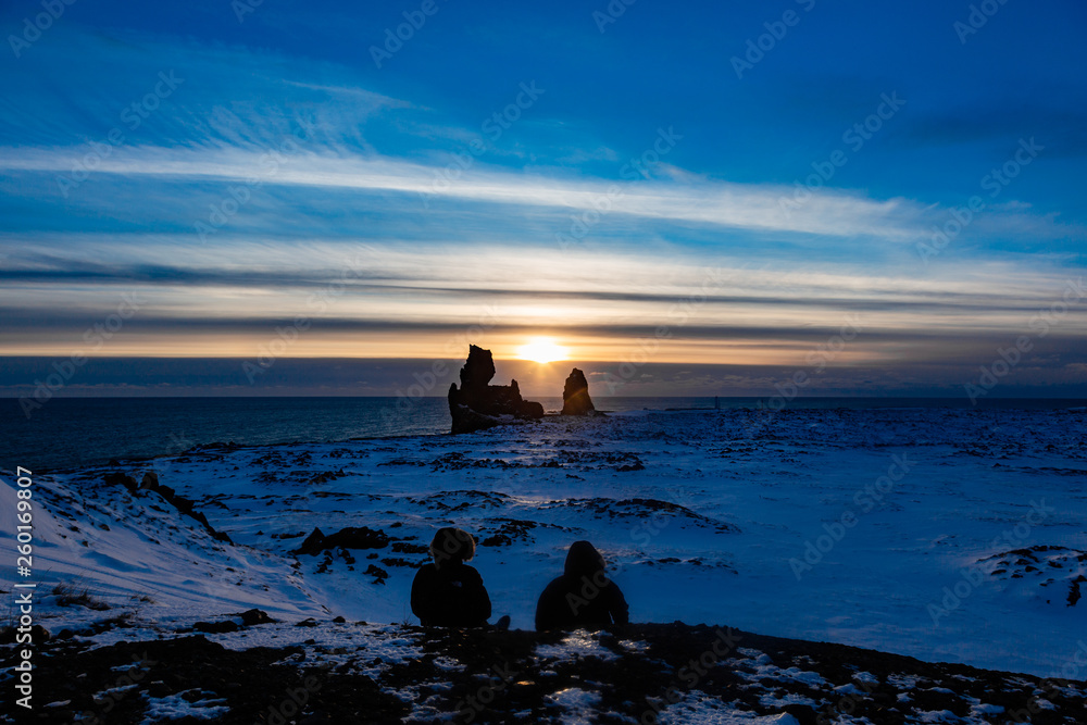 Two friends looking out over the horizon in the sunset in a snowy landscape
