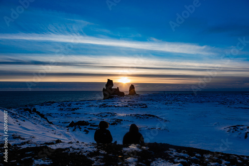 Two friends looking out over the horizon in the sunset in a snowy landscape