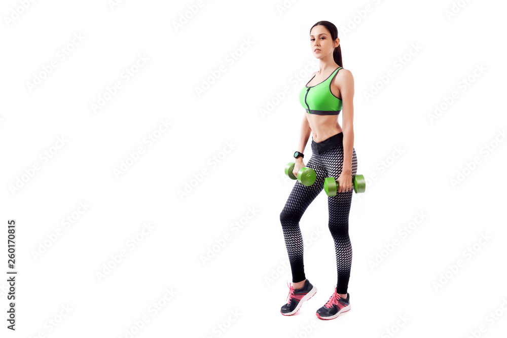 Young sportive woman fitness model brunette doing exercise with dumbbell on white isolated background. Fit girl living an active lifestyle Young sportive woman fitness model brunette doing exercise with dumbbell on white isolated background. Fit girl living an active lifestyle