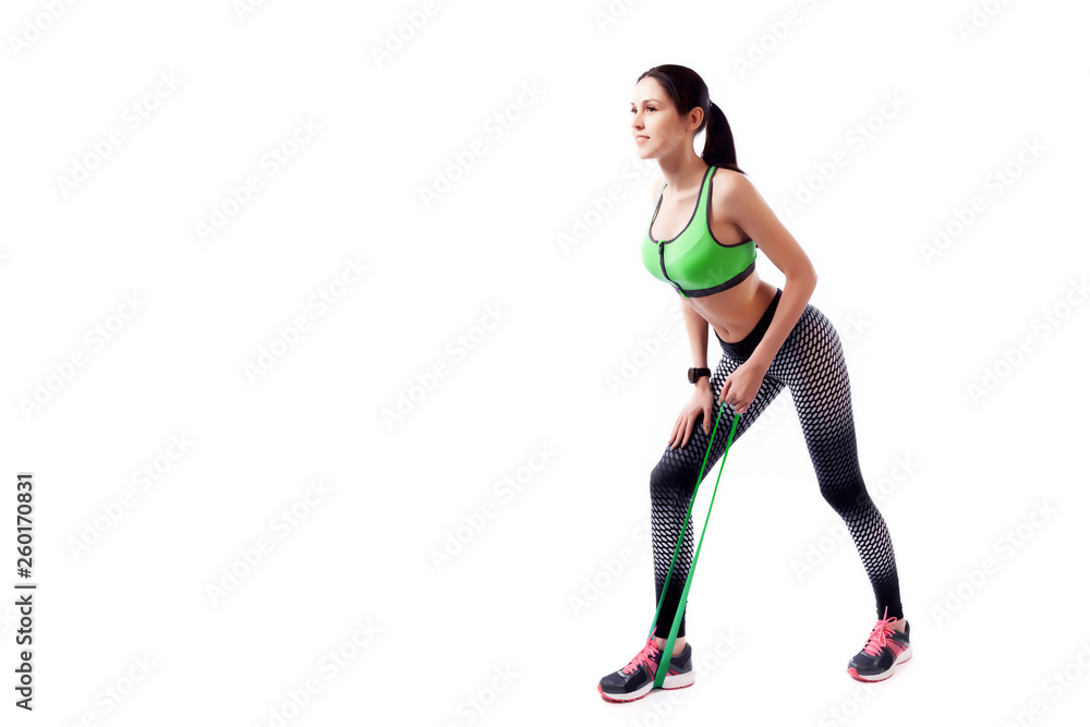 A sport woman coach in a sporty short top and gym doing sport exercise on biceps with sport fitness rubber bands on a white isolated background in studio A sport woman coach in a sporty short top and gym doing sport exercise on biceps with sport fitness rubber bands on a white isolated background in studio