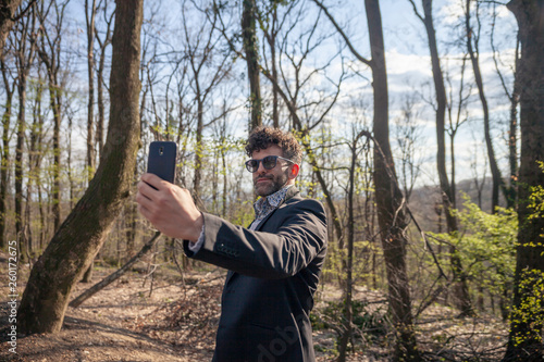 one young handsome man, talking a selfie outdoors in nature.