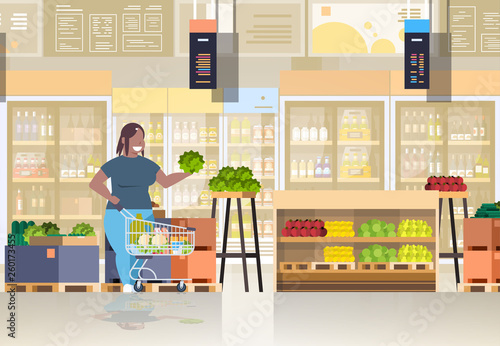 fat obese woman with shopping trolley cart choosing vegetables and fruits weight loss concept overweight african american girl supermarket customer grocery shop interior horizontal full length