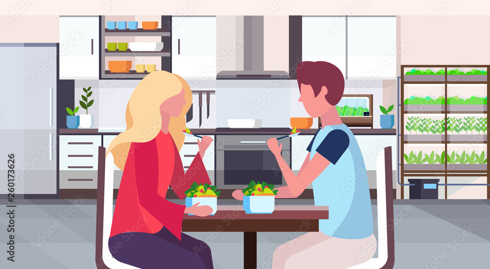 couple sitting at table man woman eating fresh fruits salad healthy food concept modern home room with smart plants growing system kitchen interior flat horizontal portrait couple sitting at table man woman eating fresh fruits salad healthy food concept modern home room with smart plants growing system kitchen interior flat horizontal portrait