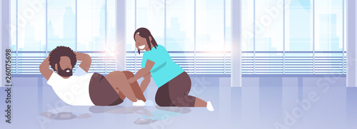 fat obese couple doing sit-ups african american overweight man woman exercising together training workout weight loss concept modern health club studio interior full length horizontal