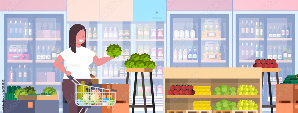 fat obese woman with shopping trolley cart choosing vegetables and fruits weight loss concept overweight girl supermarket customer grocery shop interior horizontal portrait