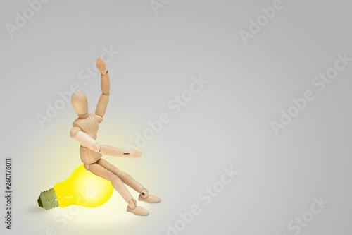 Business Creative and Idea Concept : Wooden figure mannequin sitting on yellow light bulb and put hand up over head.