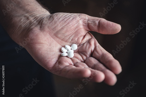 white pills in an old man's hand. concept of disease.