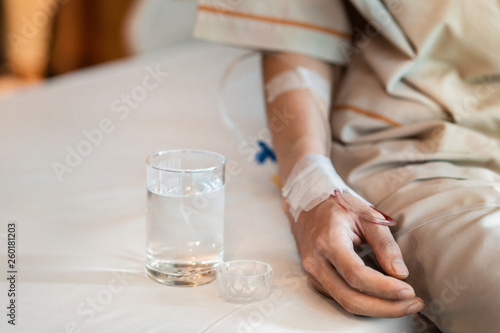 Asian man patient with medical drip or IV drip drinking water with medicine in hospital ward  Selective focus  Healthcare concept.