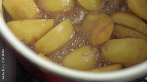 Cut peeled apple pieces cooking in hot bubbling golden brown caramel process of making pie or Tarte Tatin.