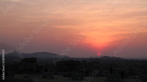 Panoramic view of tourists and travelers seated to view the beautiful sunset from the temple ruins town of Hampi, Karantaka, the ancient capital of Vijayanagara Empire in south India photo