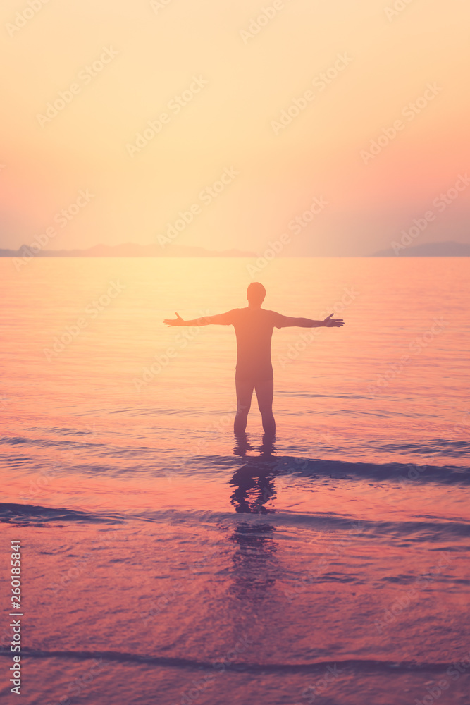 Freedom adventure and summer holiday concept. Happy man hand raise up standing on sunset beach and smooth wave abstract background.