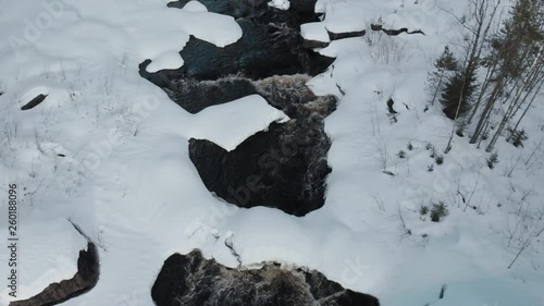 Aerial, descending, drone shot, tilting up above snowy Pamilonkoski rapids and Ala-koitajoki river, on a winter day, near Joensuu, North Karelia, Finland photo