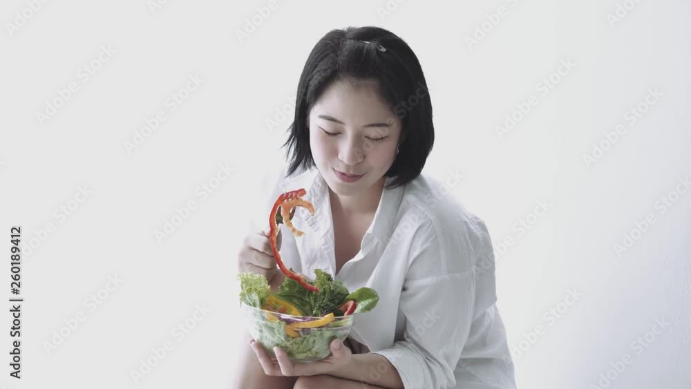 Asian woman eating salad in white living room Asian woman eating salad in white living room