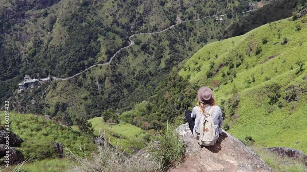 Woman traveler is sitting on the big rock in the mountain. Summer vacation. Healthy active lifestyle. Adventure day. Top view. Woman traveler is sitting on the big rock in the mountain. Summer vacation. Healthy active lifestyle. Adventure day. Top view.