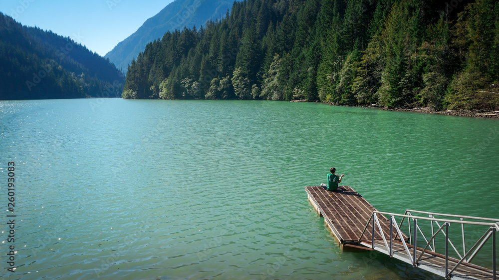 Man casting his fishing line at a mountain lake dock