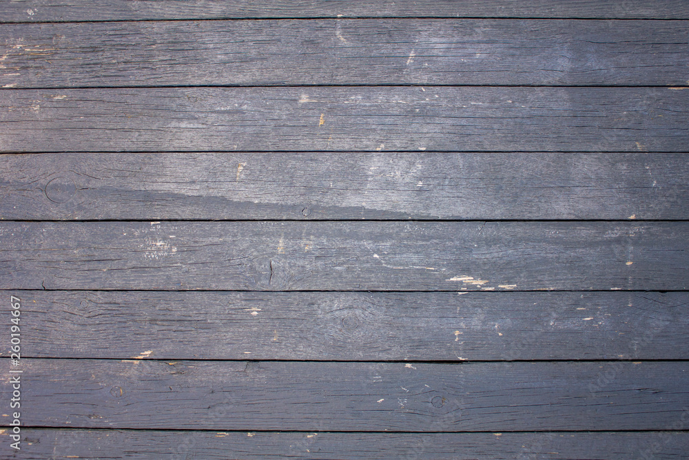 an old wooden fence of painted boards with gray peeling paint with cracks and scratches. horizontal lines. rough surface texture an old wooden fence of painted boards with gray peeling paint with cracks and scratches. horizontal lines. rough surface texture