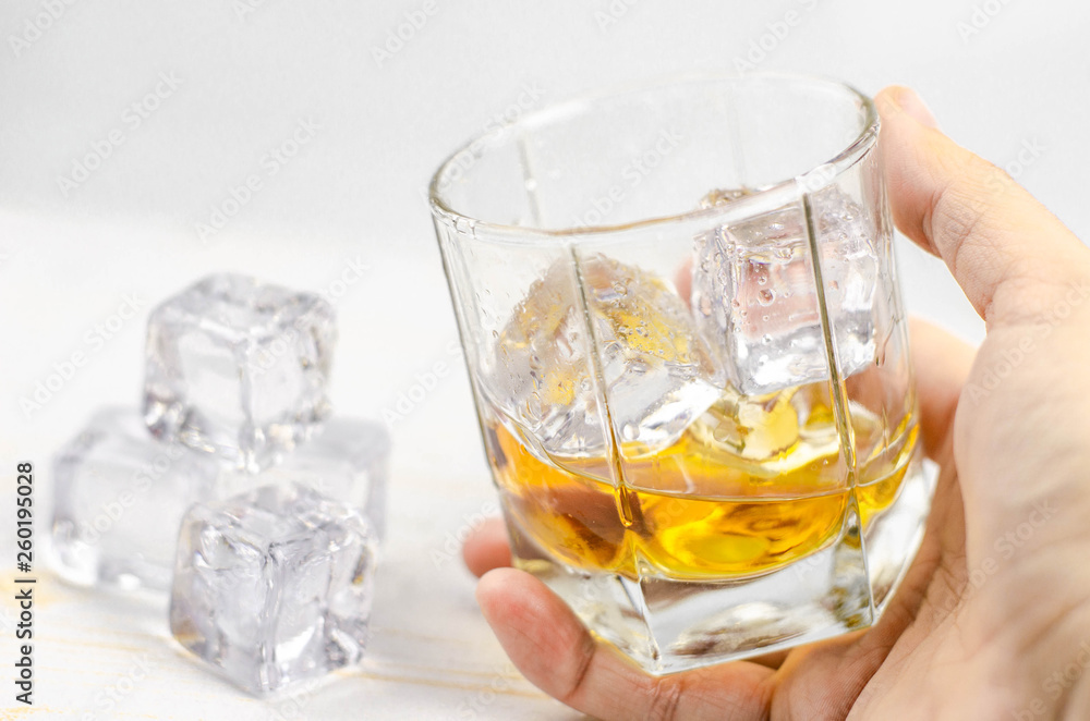 Glasses of scotch whiskey with ice cubes, white background, wooden backdrop Glasses of scotch whiskey with ice cubes, white background, wooden backdrop