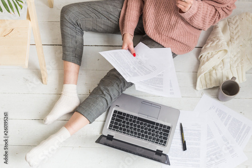 Young woman sits on the floor in a Scandinavian apartment interior with a laptop, studying law, freelance girl at work, distance learning student, online employment, paperwork and outsourcing concept