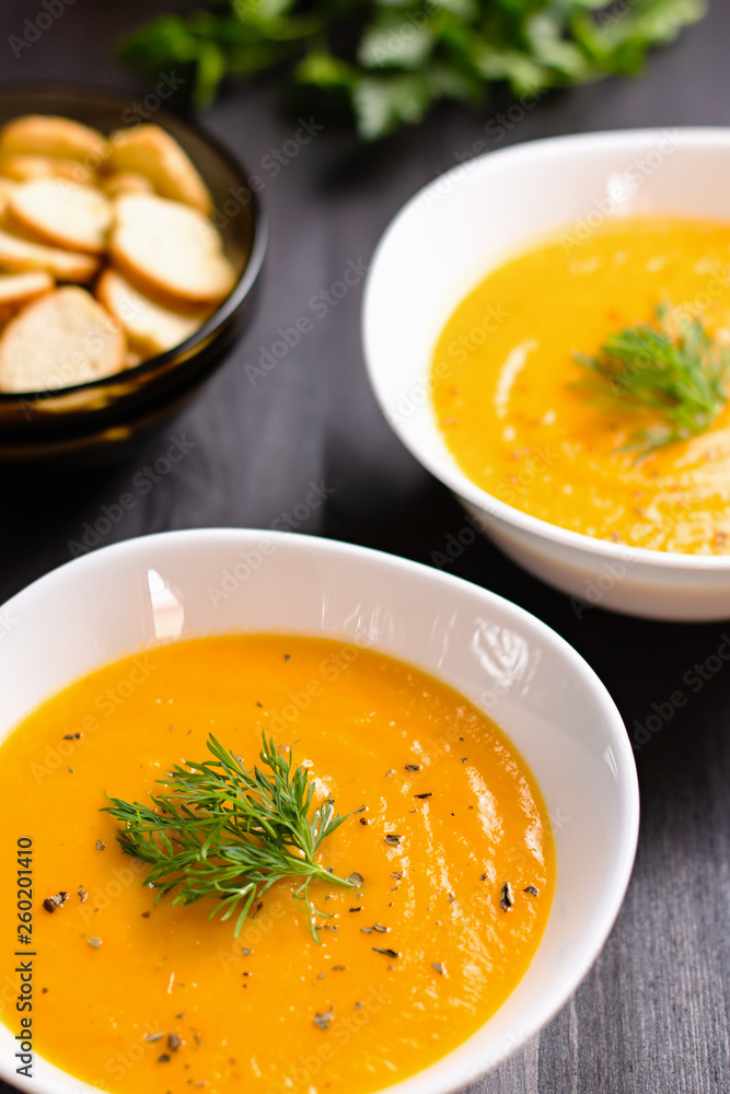 Pumpkin cream soup with croutons and fresh dill and parsley on dark wooden background, top view Pumpkin cream soup with croutons and fresh dill and parsley on dark wooden background, top view