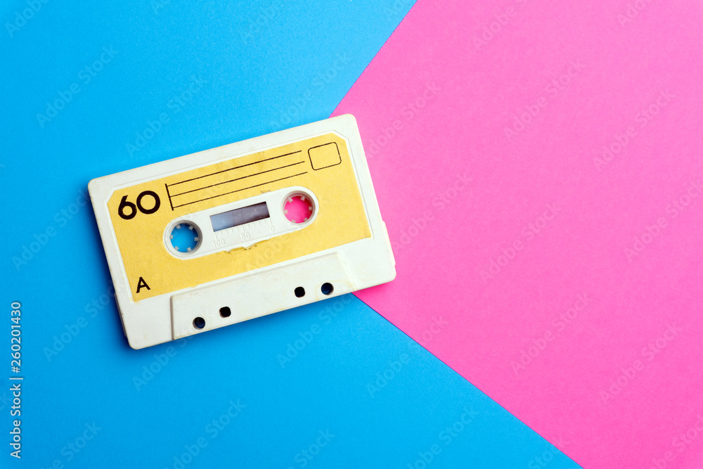 Fototapeta premium Retro old school 80-s or 90-s concept. Audio cassette on a bright blue-pink background