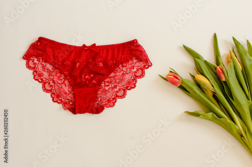 Red women underwear and spring Tulips flowers on white. Red bra and pantie. Copy space. Beauty, fashion blogger concept. Romantic lingerie for Valentine's day temptation.Erotic concept.Floral pattern.