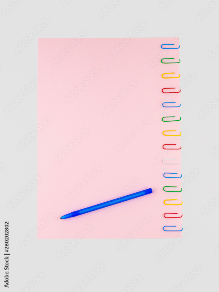 The pink sheet of paper pinned with colored paper clips, on white, with a ballpoint pen, for background, isolated on white The pink sheet of paper pinned with colored paper clips, on white, with a ballpoint pen, for background, isolated on white