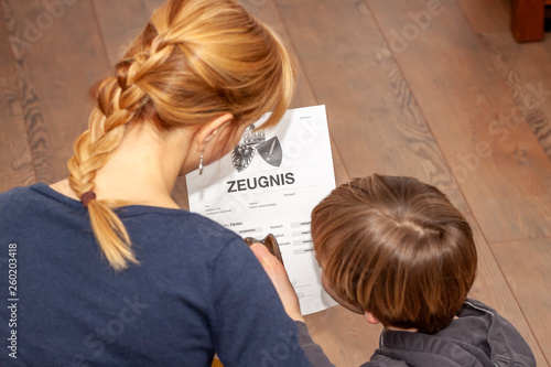 Mother holding a very bad German school certificate in her hands Translation: certificate day of birth disciplines music reading religion german english mathematics art maths insufficient grade f photo