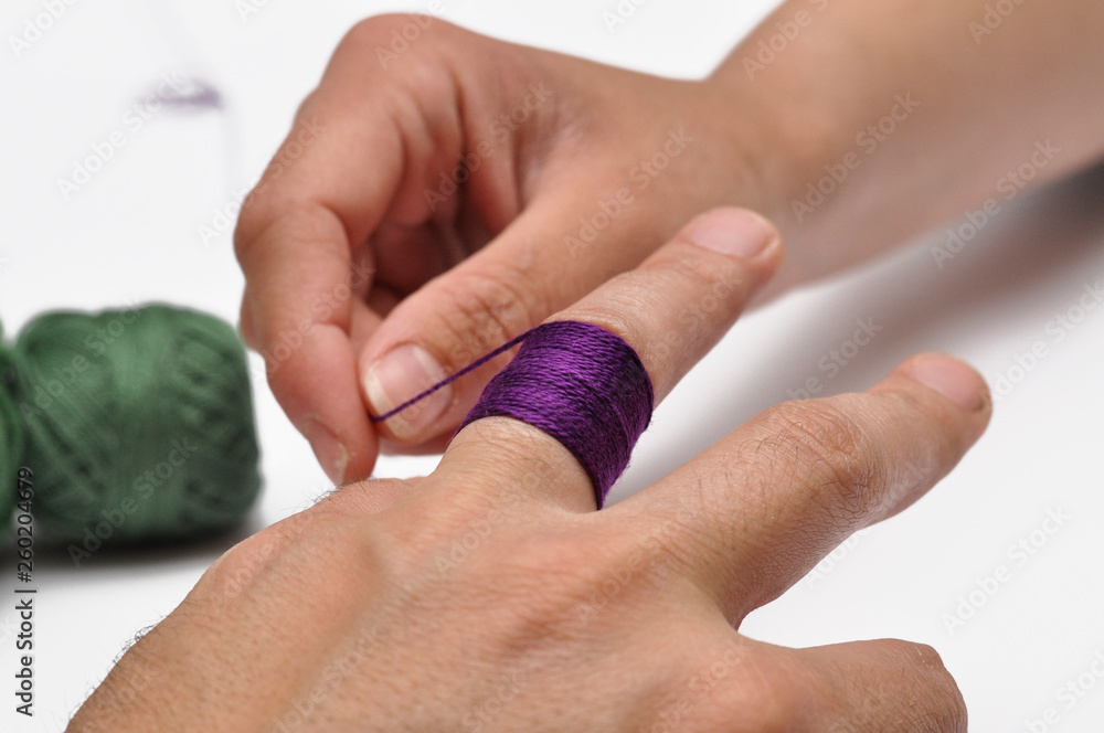 Obraz premium Man's hand and purple yarn isolated on a white background.Crochet.