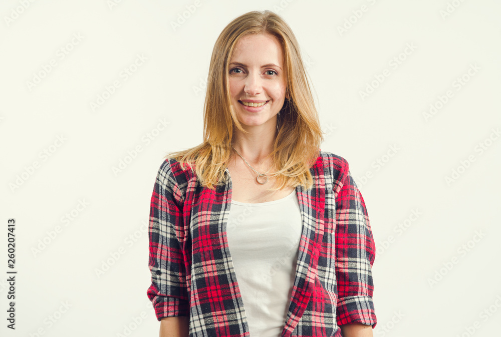 Portrait of a beautiful woman in a t-shirt and red plaid shirt standing on a light background. Portrait of a beautiful woman in a t-shirt and red plaid shirt standing on a light background.