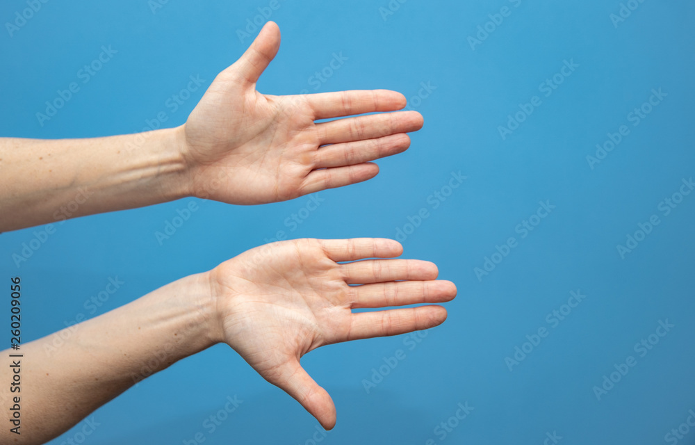 young woman showing hands on blue background. Attractive presentation of hands and nails