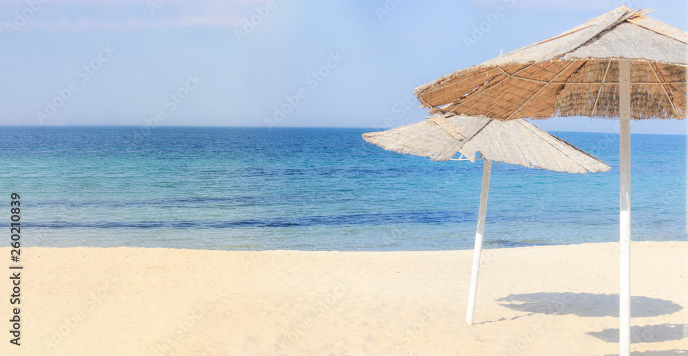 Beach umbrellas and clean sand against the backdrop of the azure coast of the sea. Vacation and Tourism concept. Beach umbrellas and clean sand against the backdrop of the azure coast of the sea. Vacation and Tourism concept.