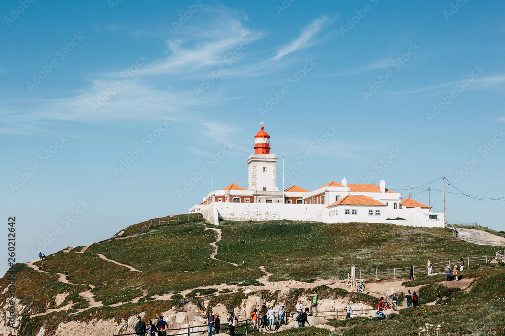 Scenic view of the lighthouse at Cape Roca in Sintra in Portugal. Nearby unrecognizable people or tourists look at the sights.