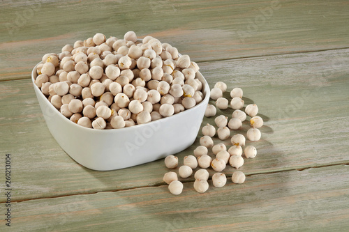 White chickpeas in white bowl on wooden background photo