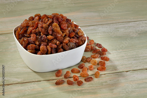 Raisins in white bowl on wooden background photo