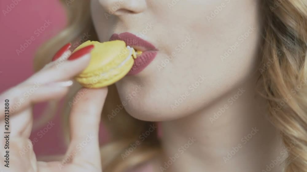 girl eating an appetizing macaroon on a colored background, a young woman bites a cookie and it crumbles, diet concept, food industry girl eating an appetizing macaroon on a colored background, a young woman bites a cookie and it crumbles, diet concept, food industry