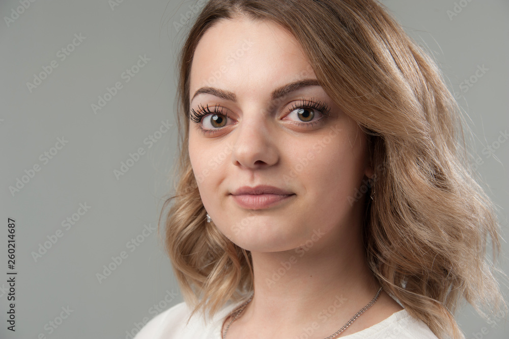 Portrait of a young attractive woman with blond hair on a neutral gray background. Portrait of a young attractive woman with blond hair on a neutral gray background.