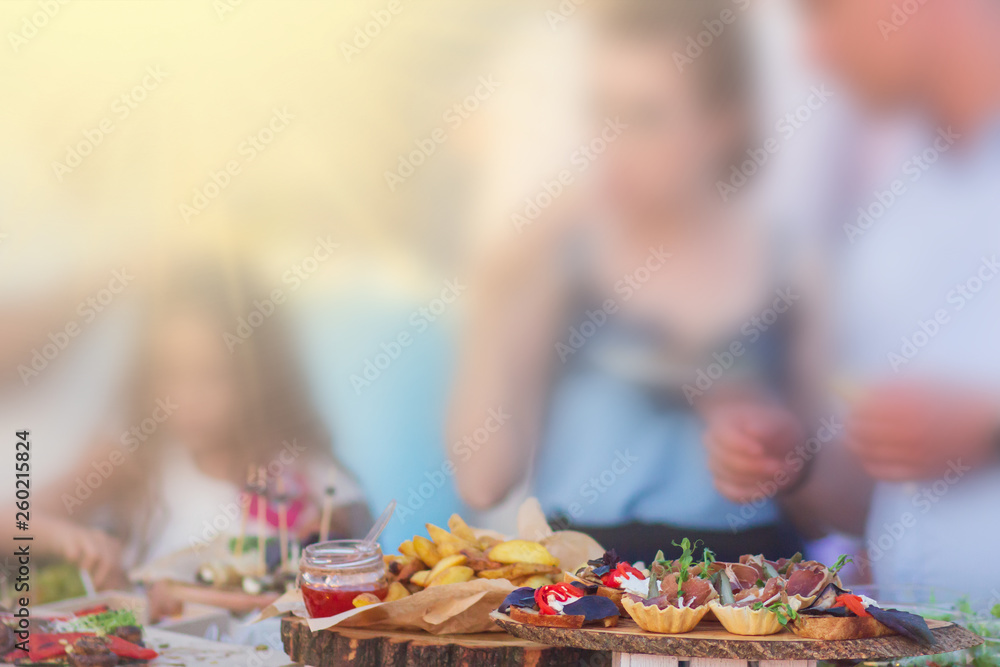 Fototapeta premium Beautifully decorated catering banquet table with different food snacks and appetizers with sandwich at sunny day