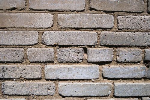 Fragment of weathered wall of old building made of grey bricks. Abstract texture background