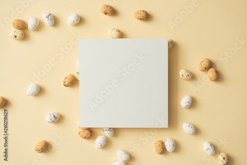Easter eggs on pastel yellow background with paper card note. Easter holiday concept. Minimal composition.