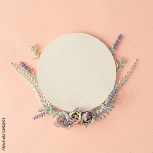 Creative layout made with spring flowers and leaves on pastel pink background. Minimal nature composition with paper card copy space.